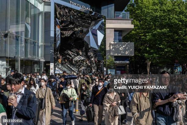People cross a street in Omotesando shopping district of Tokyo on April 9, 2023.