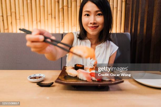 woman eating sushi in a traditional japanese restaurant - eating seafood stock pictures, royalty-free photos & images