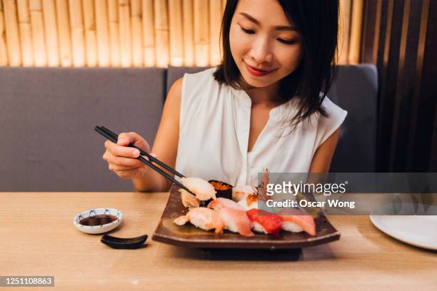 woman eating sushi in a traditional japanese restaurant - woman sushi stock-fotos und bilder