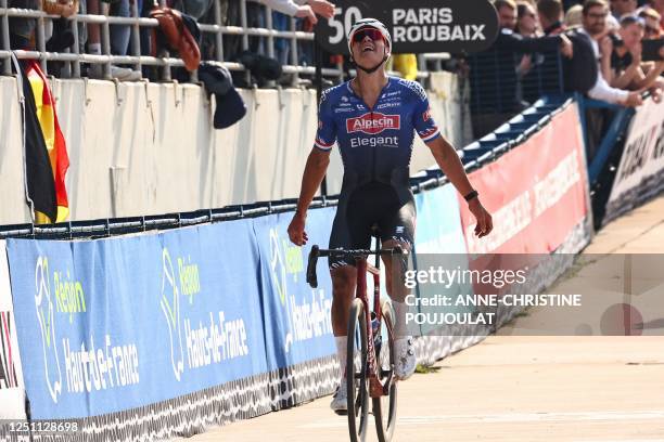 Alpecin-Deceuninck team's Dutch rider Mathieu Van Der Poel celebrates as he cycles to the finish line to win the 120th edition of the Paris-Roubaix...