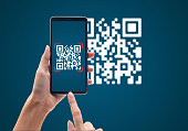 Hand using mobile smart phone scan Qr code on blue background. Cashless technology and digital money concept