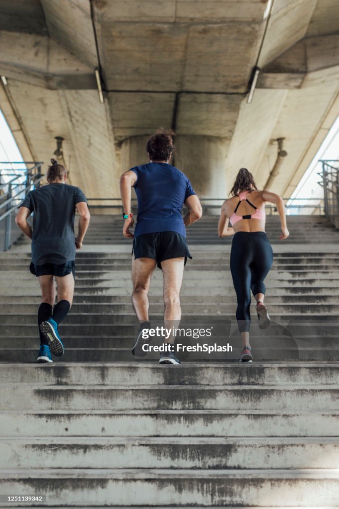 Vue arrière de trois coureurs déterminés exerçant dans un environnement urbain