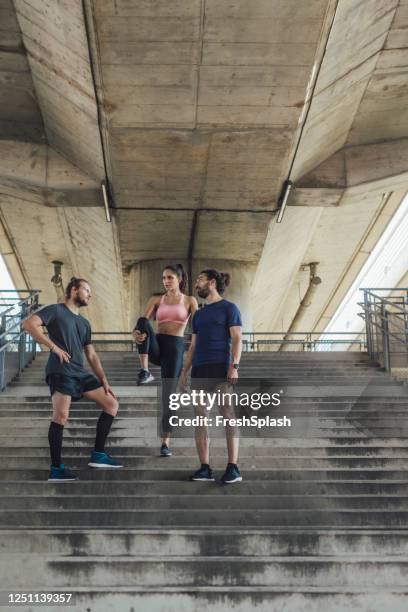 groep van drie vrienden die zich na het lopen in openlucht samen uitrekken - maillot de sport stockfoto's en -beelden