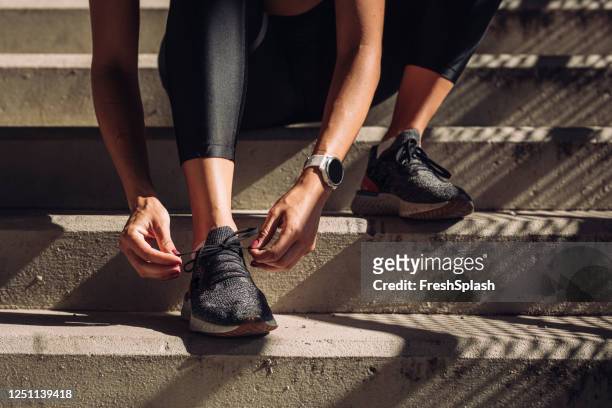 unrecognizable sportswoman tying laces on running sneakers, a close up - tied up stock pictures, royalty-free photos & images