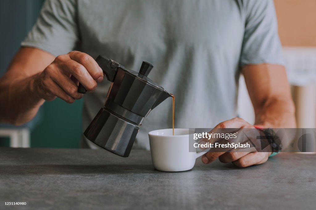 Hands of an Anonymous Man Pouring Himself Coffee in the Office