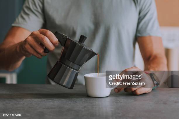 mani di un uomo anonimo che si versa il caffè in ufficio - moka foto e immagini stock