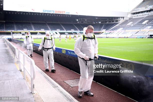 Staff disinfects the areas around the pitch during the Premier League match between Newcastle United and Sheffield United at St. James Park on June...