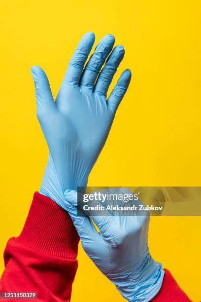the woman puts on protective medical gloves. - surgical glove stock pictures, royalty-free photos & images