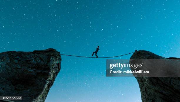 wandelen op touw tussen twee kliffen en het houden van de balans - tightrope stockfoto's en -beelden