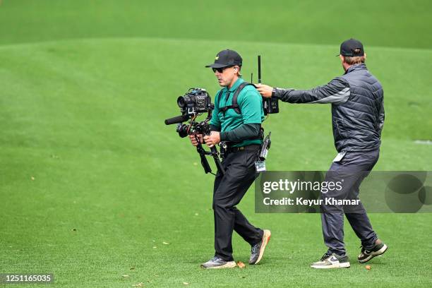 Camera operator films players as they walk off the 18th hole during the continuation of the weather-delayed third round of the 2023 Masters...