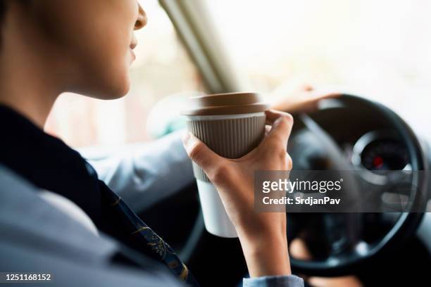 close-up van een vrouwelijke hand die een koffiekop in een auto houdt - drink driving stockfoto's en -beelden