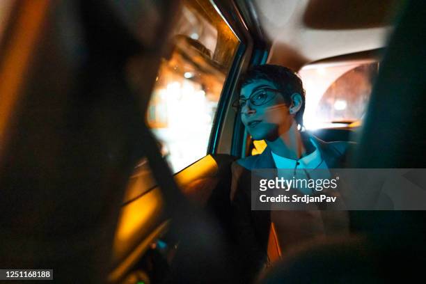 jonge onderneemster die uit het autovenster bij nacht kijkt - reden stockfoto's en -beelden