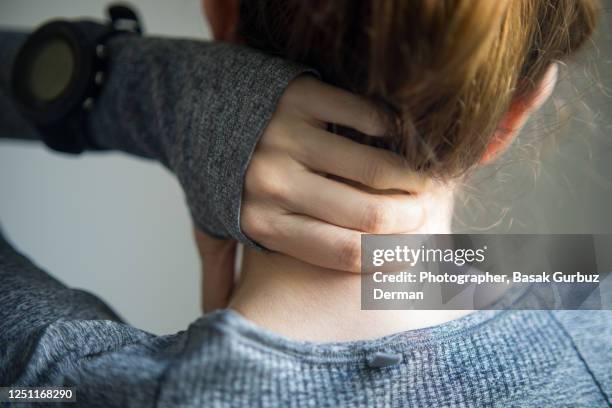 rear view of a woman holding her neck - neck pain stock pictures, royalty-free photos & images