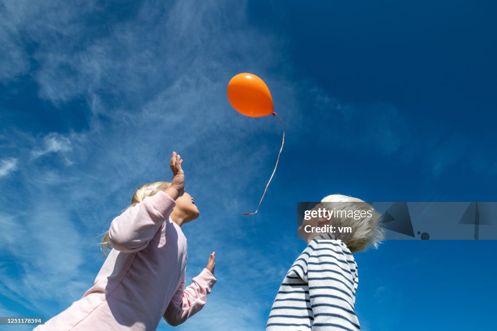 Broer en zuster die een ballon vrijgeven