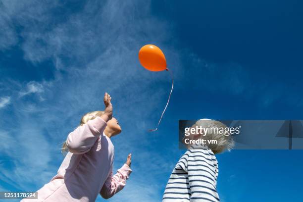 brother and sister releasing a balloon - releasing stock pictures, royalty-free photos & images