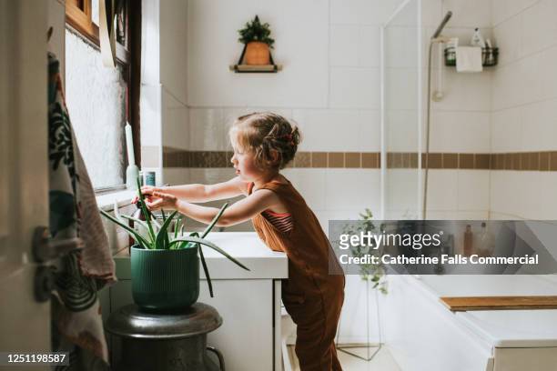 little girl washing her hands at a bathroom sink - domestic bathroom stock pictures, royalty-free photos & images