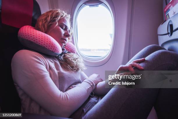 una pasajera que duerme con el cojín del cuello en el avión. - window seat fotografías e imágenes de stock