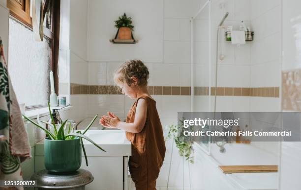 little girl washing her hands at a bathroom sink - bathroom sink stock-fotos und bilder