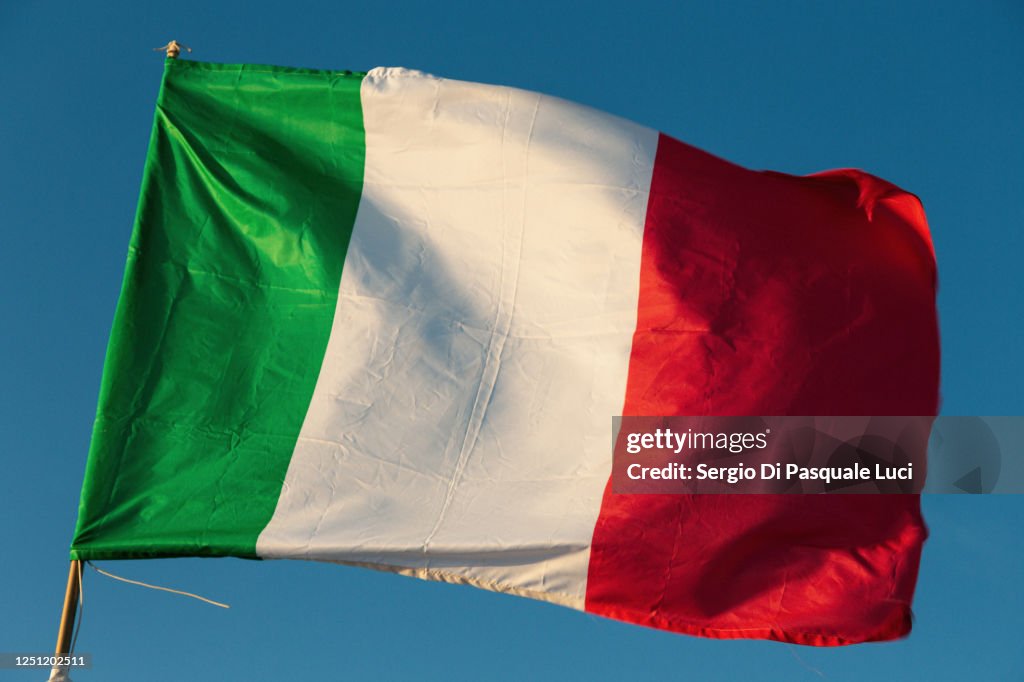 Italian flag flying in the wind with a blue sky background