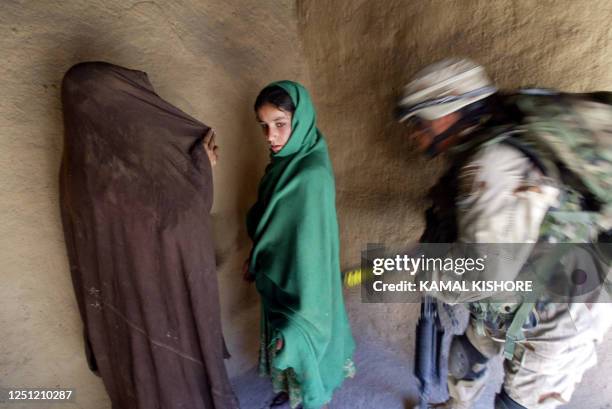 An American soldier rushes to frisk Afghan women villagers during Operation Deliberate Strike, some 60 kilometers north of Kandahar, Afghanistan, 19...