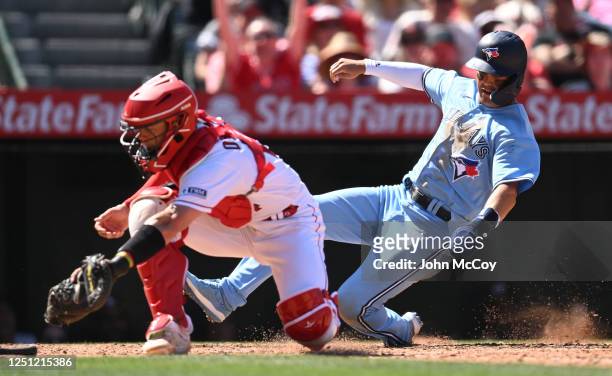 Whit Merrifield of the Toronto Blue Jays scores ahead of the throw to Logan O'Hoppe of the Los Angeles Angels in the sixth inning at Angel Stadium of...