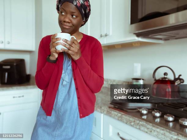 woman drinks coffee while watching tv from kitchen - cardigan stock pictures, royalty-free photos & images