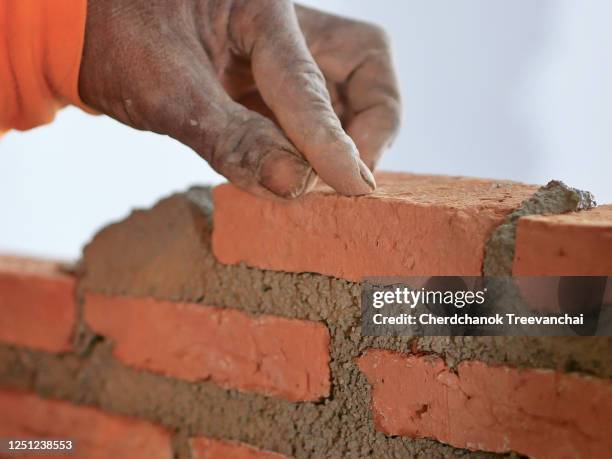 worker installing red brick on the cement layer - mason bricklayer stock pictures, royalty-free photos & images