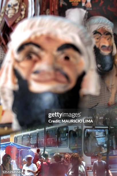 The reflection of pedestrians is seen in this store window selling masks with the face of Osama Bin Laden 24 October 2001. La imagen de los...