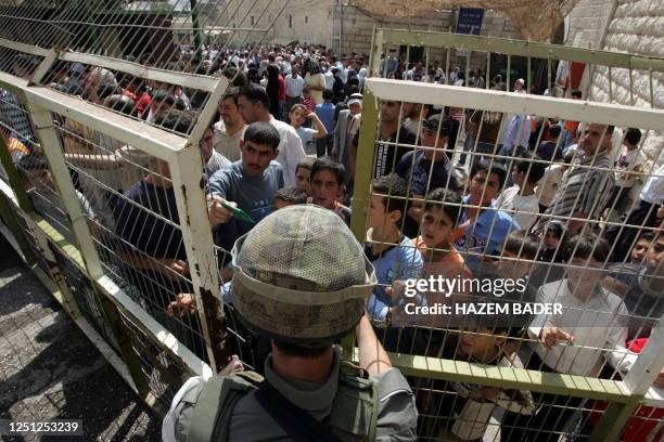 Palestinian Muslim worshippers wait to be allowed across an Israeli manned checkpoint to take part in Friday noon prayers close to the Tomb of the...