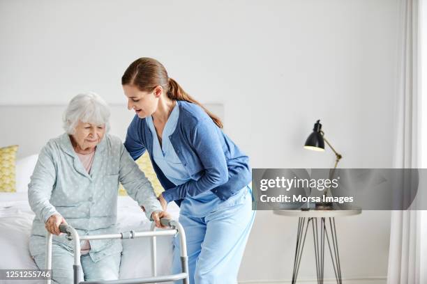 caregiver supporting disabled woman in standing - carer stock-fotos und bilder
