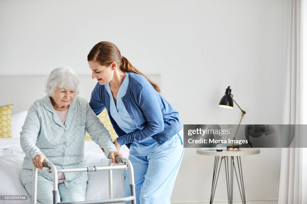 Caregiver supporting disabled woman in standing