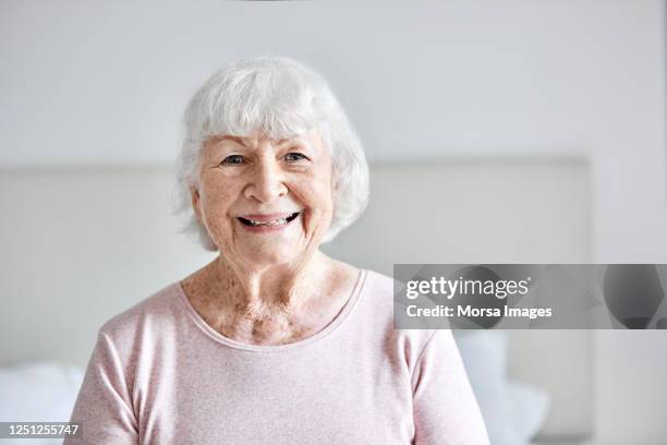 smiling senior woman at home - alleen seniore vrouwen stockfoto's en -beelden