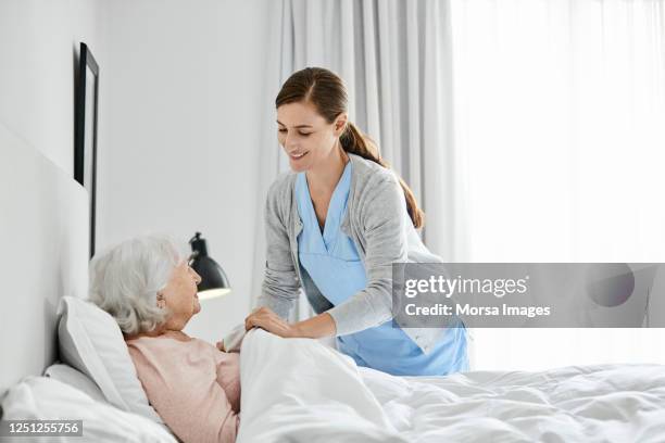 elderly woman with caregiver at home - old bed stockfoto's en -beelden