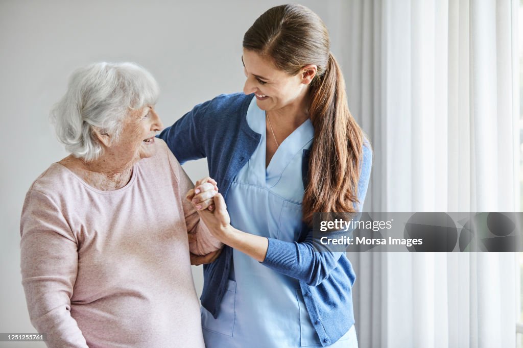 Smiling nurse assisting senior female in walking