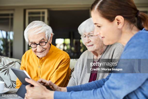 nurse discussing with senior couple over tablet pc - care stock-fotos und bilder
