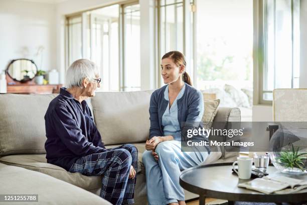 senior man discussing with female nurse - nurse helping old woman at home stockfoto's en -beelden