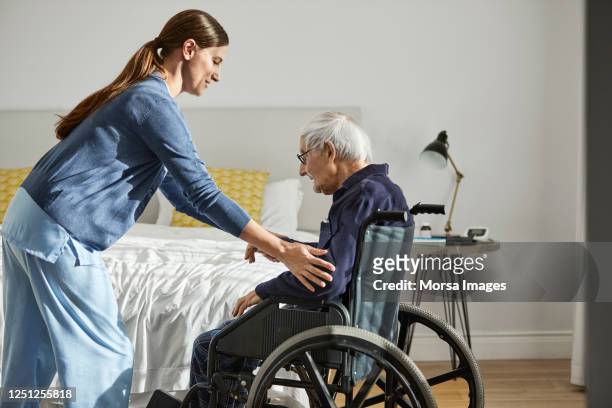 caregiver assisting senior man on wheelchair - care stock-fotos und bilder