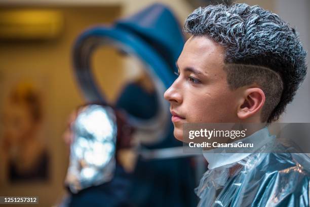 late teen boy dans le salon de coiffure en attente de teinture pour cheveux à sécher - teenagers cheveux colorés photos et images de collection