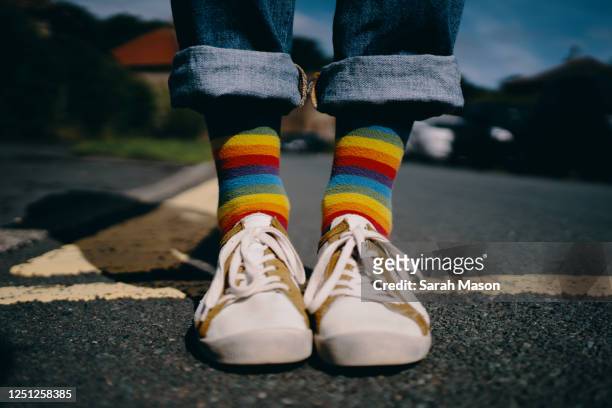 pair of feet wearing trainers and rainbow socks - hochgekrempelte hose stock-fotos und bilder