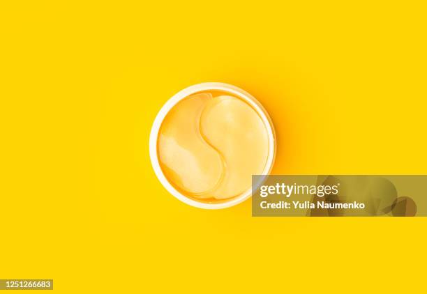 golden patches on a yellow background. natural flower extract cosmetics, beauty and fashion. patches for moisturizing in a jar, flat lay, top view. - korean beauty products stock pictures, royalty-free photos & images