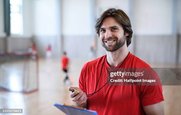 portrait of children teacher or instructor indoors in gym class, looking at camera. - physical education stock pictures, royalty-free photos & images