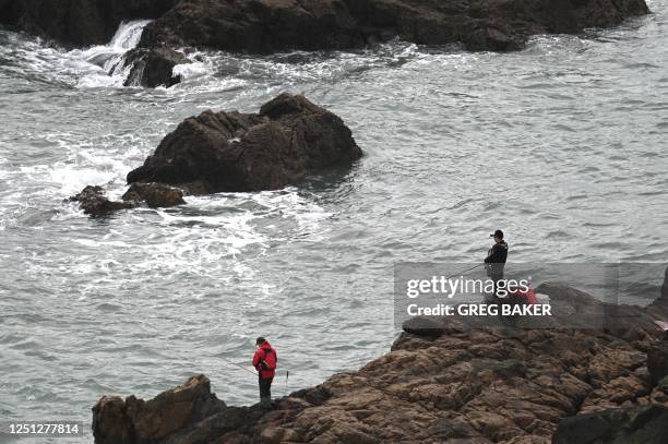 Two men fish from rocks on Pingtan island, opposite Taiwan, in Chinas southeast Fujian province on April 10, 2023. - China was due to hold live-fire...