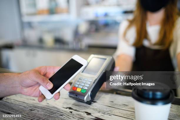 young waiter with face mask and gloves serving coffee in coffee shop, contactless payment concept. - pago-sin-contacto fotografías e imágenes de stock