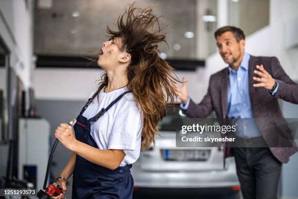 female mechanic having fun with air pump in auto repair shop. - air quality stock pictures, royalty-free photos & images
