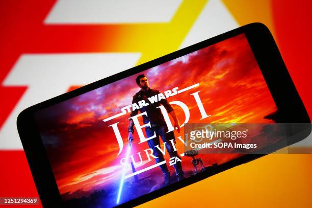 In this photo illustration, Star Wars Jedi: Survivor logo of a video game is seen on a smartphone and EA logo on a pc screen.