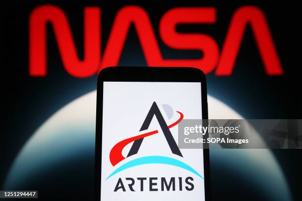 In this photo illustration, Artemis 2 logo is seen on a smartphone and NASA logo on a pc screen.