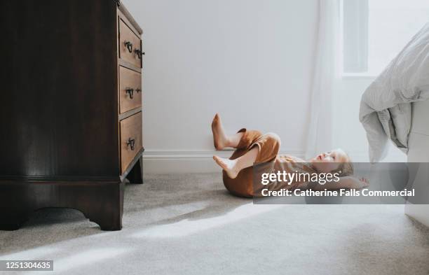 child's lying on grey thick pile carpet, casting shadow - nylon feet stock-fotos und bilder