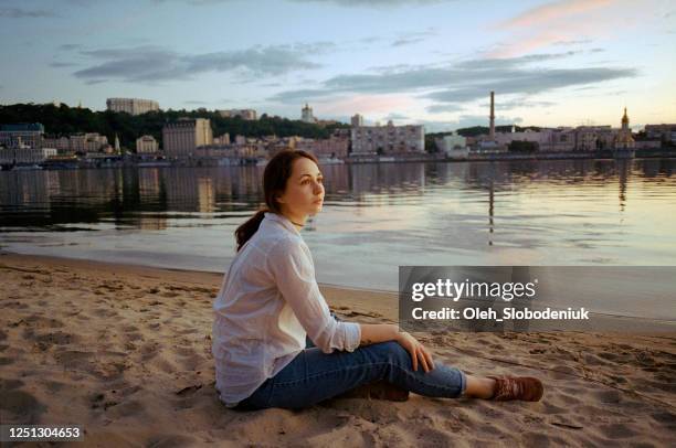 woman sitting on beach on the background of kyiv cityscape - dnieper river stock pictures, royalty-free photos & images