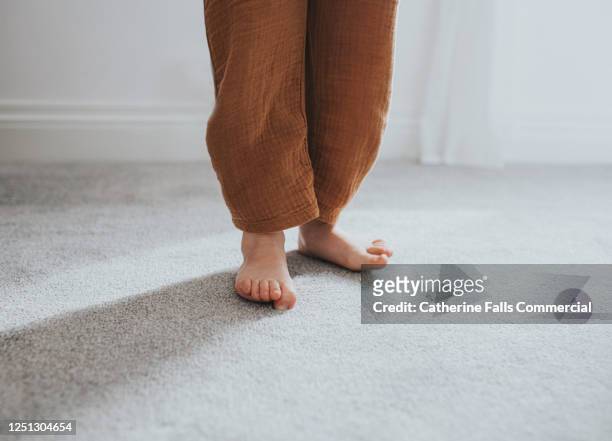 child's wiggling toes on grey thick pile carpet, casting shadow - nylon feet stock-fotos und bilder