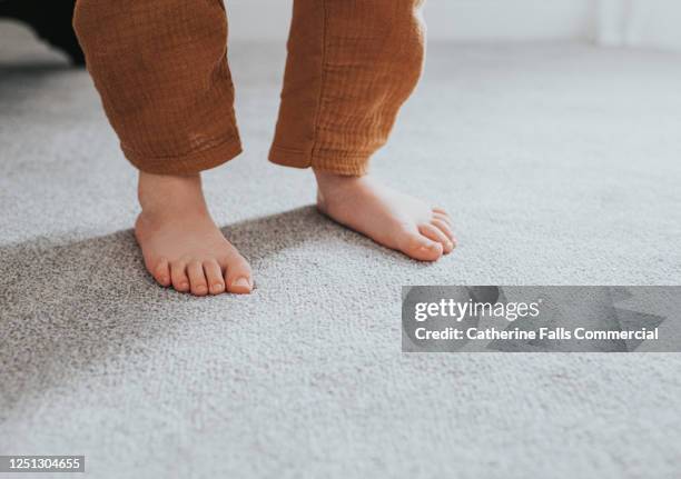 child's feet on grey thick pile carpet, casting shadow - nylon feet stock-fotos und bilder